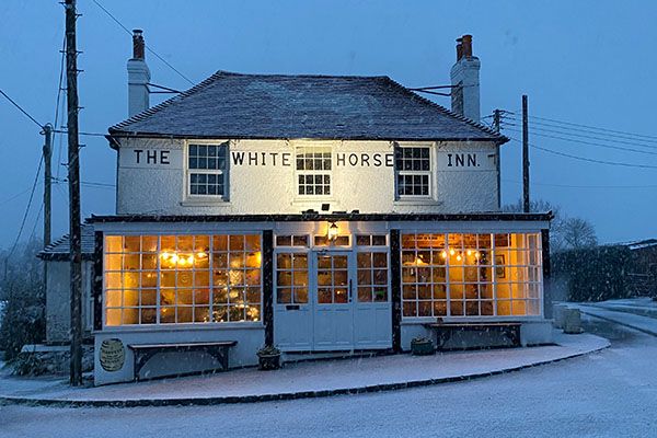 The pub lit up at dusk after snow